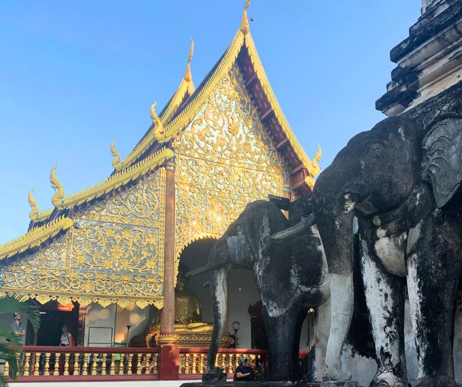 Elefantes de piedra en primer plano y templo Wat Chiang Man al fondo